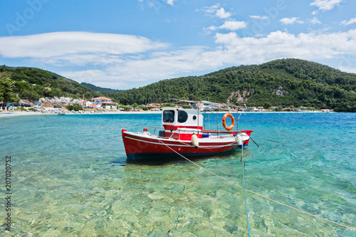 Small red fishing boat at Panormos bay in front of Panormos beach, island of Skopelos, Greece