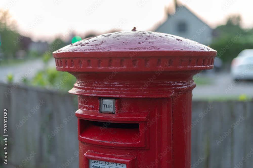 bright red post box with old black and white building in background and sign set to Tuesday for next collection bright red post box with old black and white building in background and sign set to Tuesday for next collection