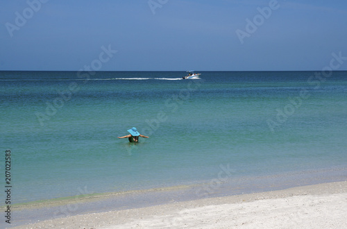 A woman enjoys wading into the warm water of the Gulf of Mexico at St. Pete Beach, Florida on a warm April 