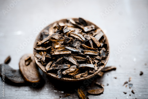 Popular Indian and Asian mukhwas or mouth freshner i.e.  Aam Ki Ghuthli Ka Mukhwas consisiting of ghee and hard boiled mango seeds in a bowl on wooden surface. photo