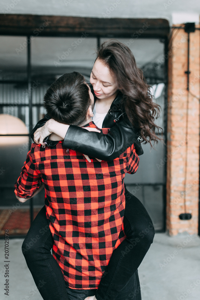 charismatic couple at a photo shoot in European style. Hugging and smiling looking at each other. The casual look and the light airy dress of the girl. the loft Studio, and a beautiful girl charismatic couple at a photo shoot in European style. Hugging and smiling looking at each other. The casual look and the light airy dress of the girl. the loft Studio, and a beautiful girl