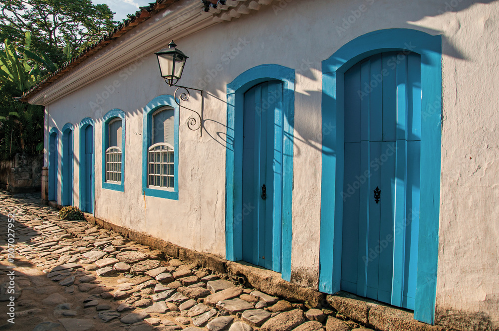 Naklejka premium Overview of cobblestone street with old houses at the sunset in Paraty, an amazing and historic town totally preserved in the coast of the Rio de Janeiro State, southwestern Brazil