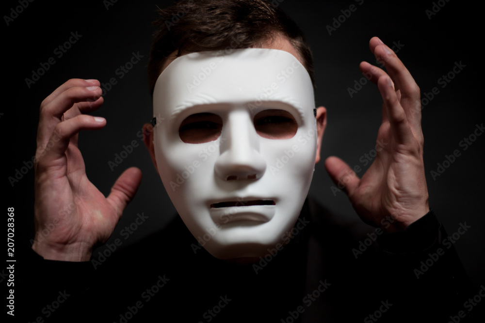 Close-up of a man in a white mask, with his arms raised