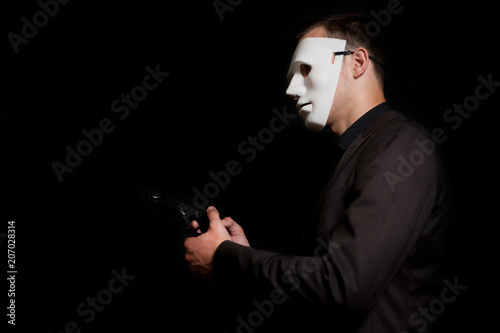 A man with a gun in his hand, in a white mask on a black background.