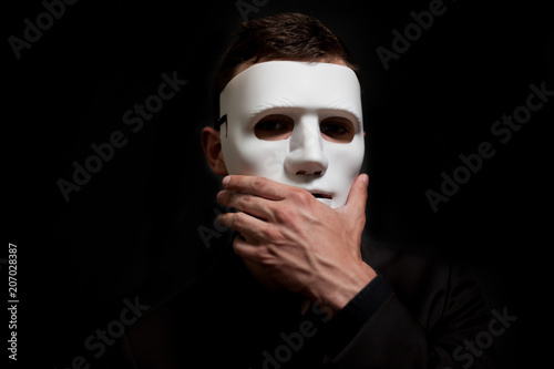 Close-up of a man in a white mask, surprise, thoughtfulness. Touches a hand to the mask
