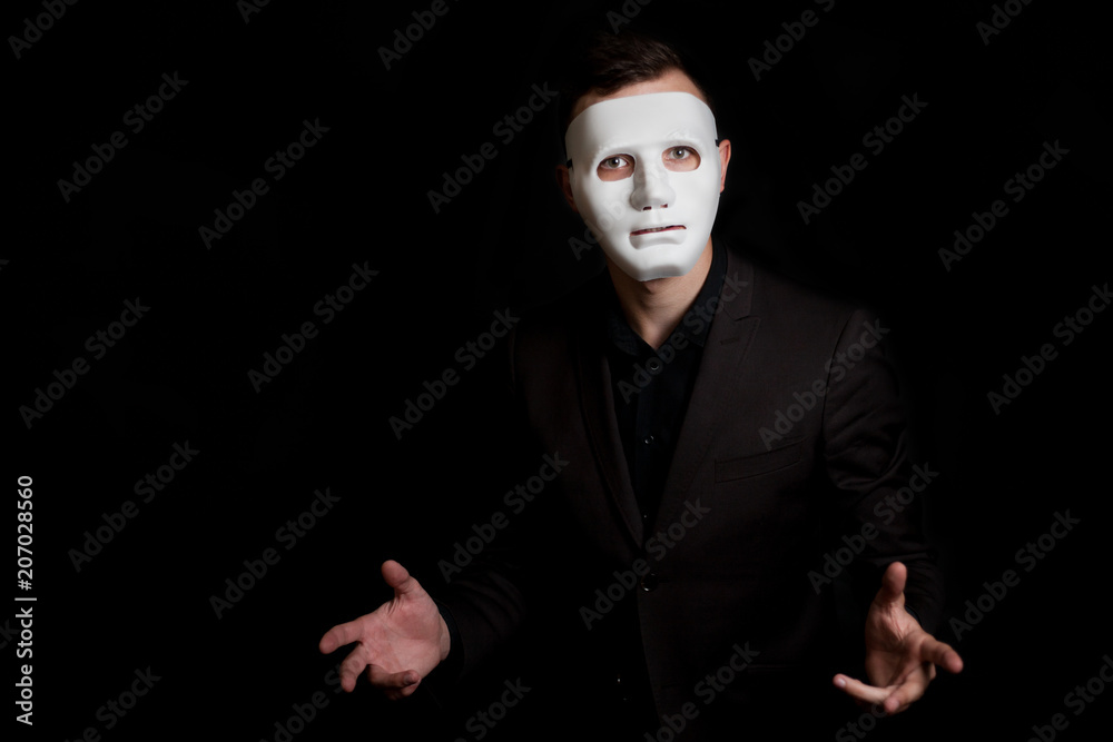 Портрет мужчины в белой маске на черном фоне. Мимика рук