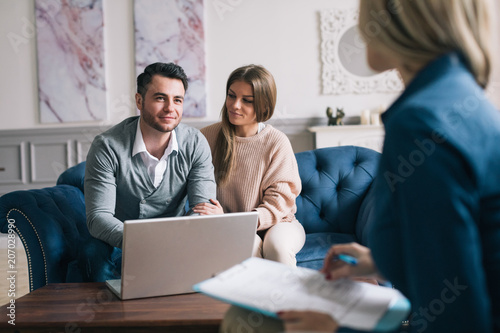 Happy couple planning their future while consulting with insurance agent in their home.