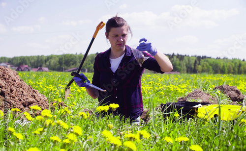 Scientist ecologist on the meadow taking samples of the soil and putting them in the plastic bag.