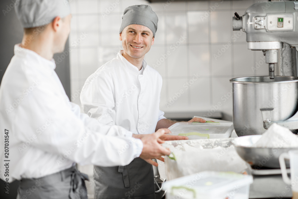 Two male confectioners preparing ingredients for baking standing at the manufacturing Two male confectioners preparing ingredients for baking standing at the manufacturing