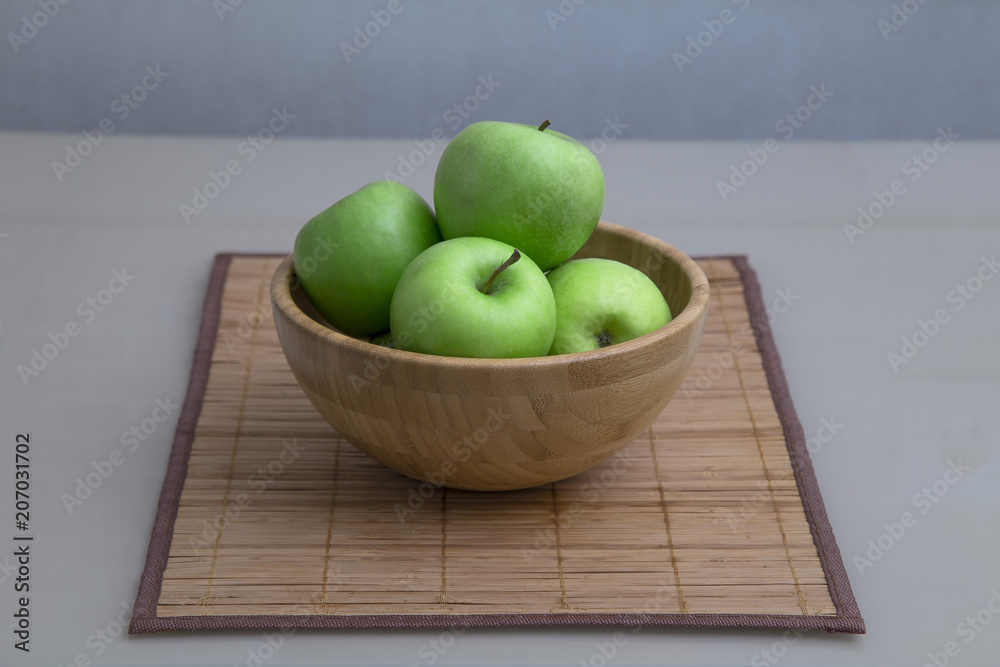 green fresh apples are in a wooden bowl in the kitchen green fresh apples are in a wooden bowl in the kitchen