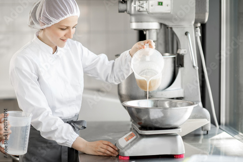 Εκτύπωση καμβά Woman confectioner in uniform weighing ingredients for pastry working at the bak