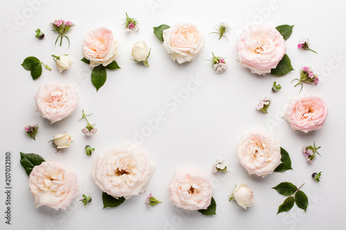 Floral frame made of pink roses and green leaves on white background. Flat lay, top view. Valentine's background. © LyubaAlex