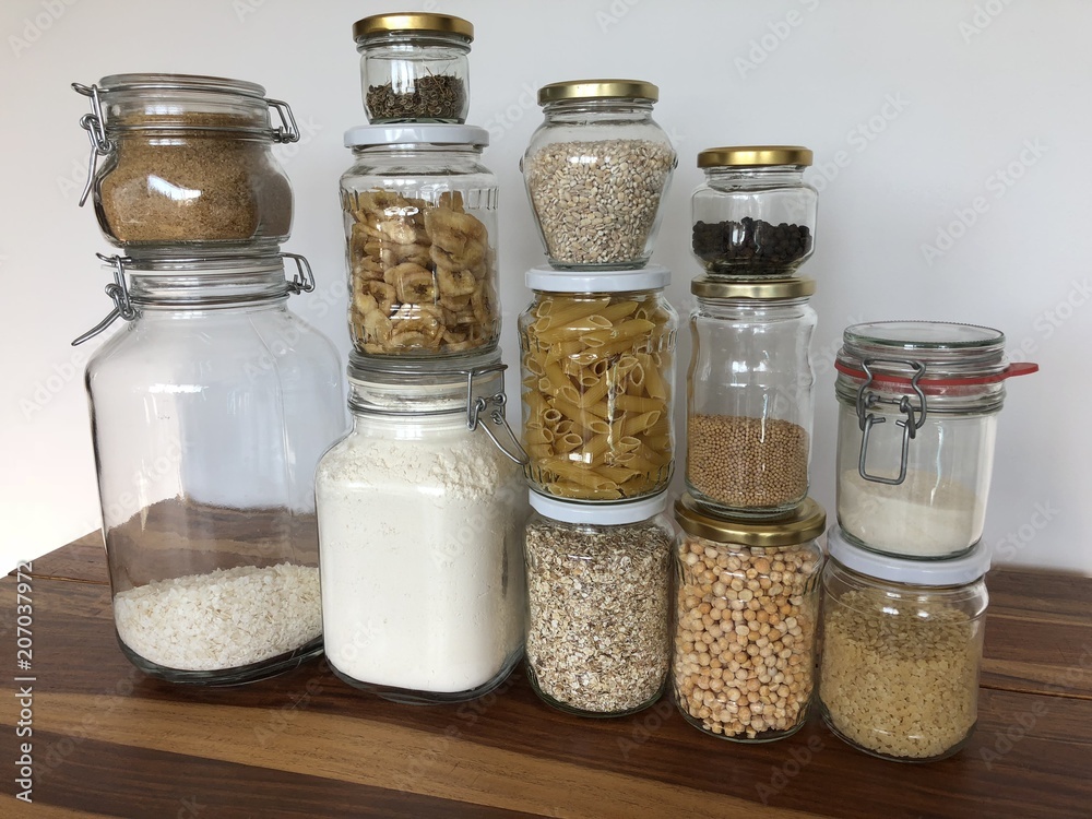 Healthy cereals and fruits in glass jars and reusable bags with fresh basil on wooden background in daylight Healthy cereals and fruits in glass jars and reusable bags with fresh basil on wooden background in daylight
