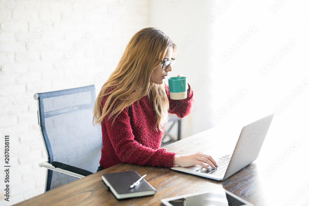 Woman having coffee while working on laptop Woman having coffee while working on laptop