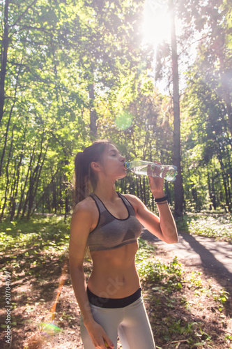 Young woman drinking water after running outdoors