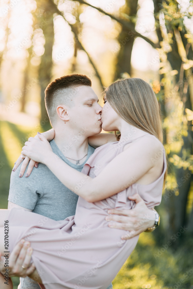 Fototapeta premium Beautiful young couple in the Park on a Sunny day, loving and happy. Walk and laugh. Pre-wedding shooting in nature. Casual style in clothing and European in processing