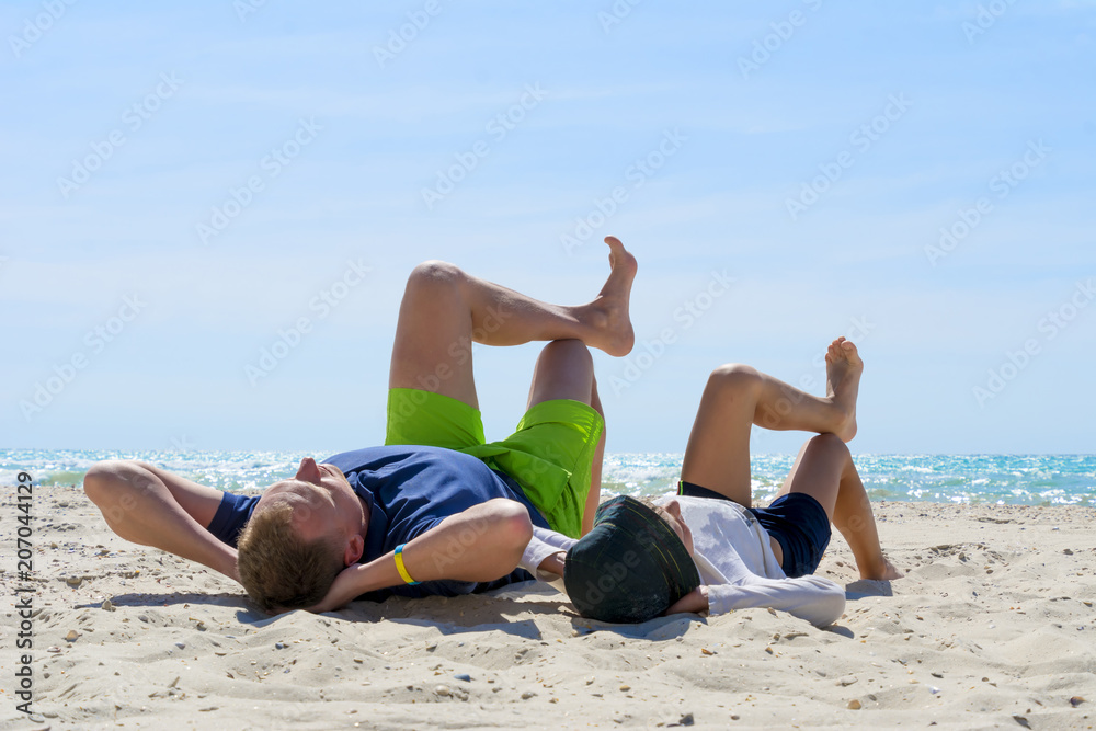 father and son having fun on the beach, laying on a beach father and son having fun on the beach, laying on a beach
