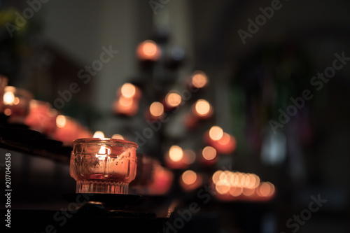 Opferkerze in Kirche, Spende, Lichtpunkte im Hintergrund