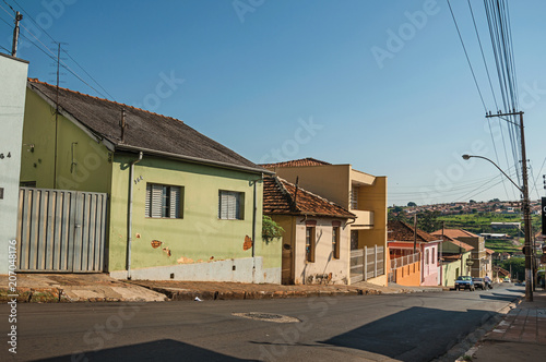 Downhill street view with sidewalk walls and colorful houses on a sunny day at São Manuel. A cute little town in the countryside of São Paulo State. Southeast Brazil. photo