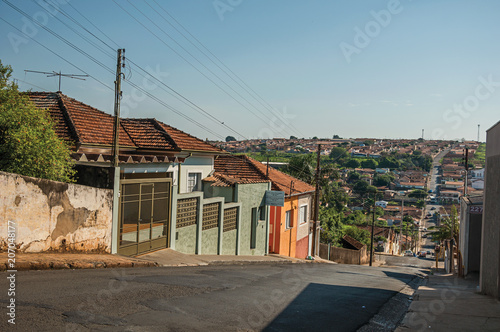 Downhill street view with sidewalk walls and colorful houses on a sunny day at São Manuel. A cute little town in the countryside of São Paulo State. Southeast Brazil.