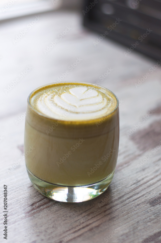 Trendy multicolored lattes. Top view of hot green tea milk or avocado or matcha tea taste with latte art in a cup on wood table. Beautiful foam, glass cups, stylish toning, space for text. Trendy multicolored lattes. Top view of hot green tea milk or avocado or matcha tea taste with latte art in a cup on wood table. Beautiful foam, glass cups, stylish toning, space for text.