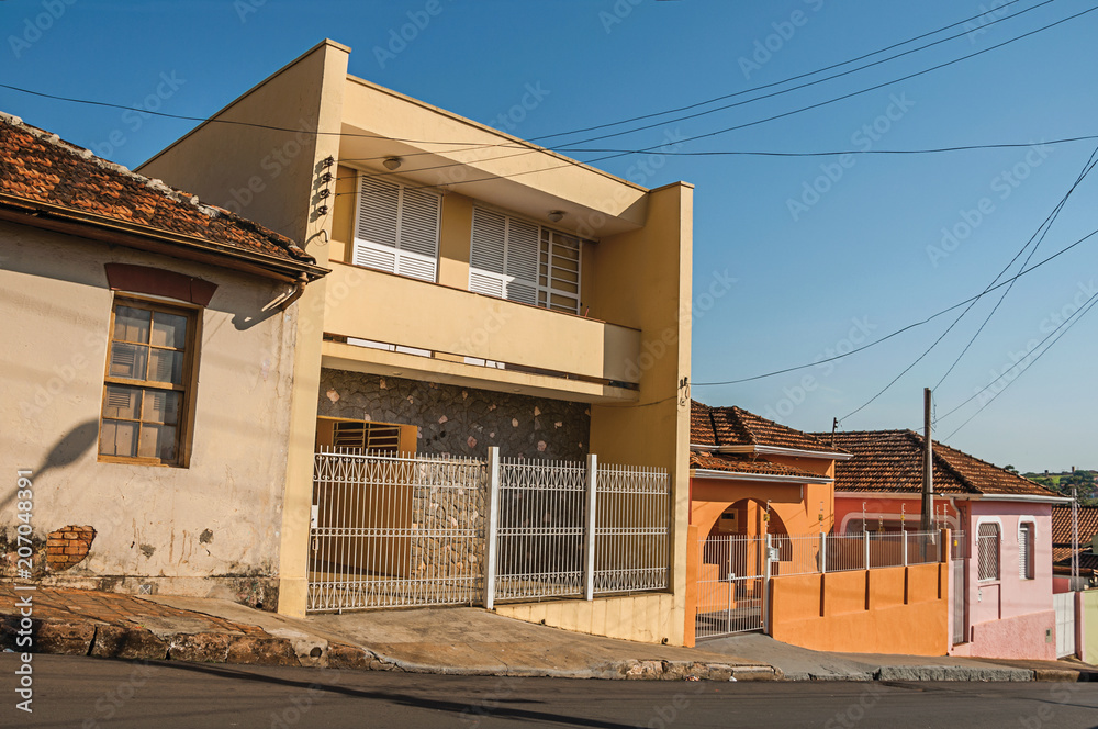 Working-class colored houses and fences in an empty street on a sunny day at São Manuel. A cute little town in the countryside of São Paulo State. Southeast Brazil.