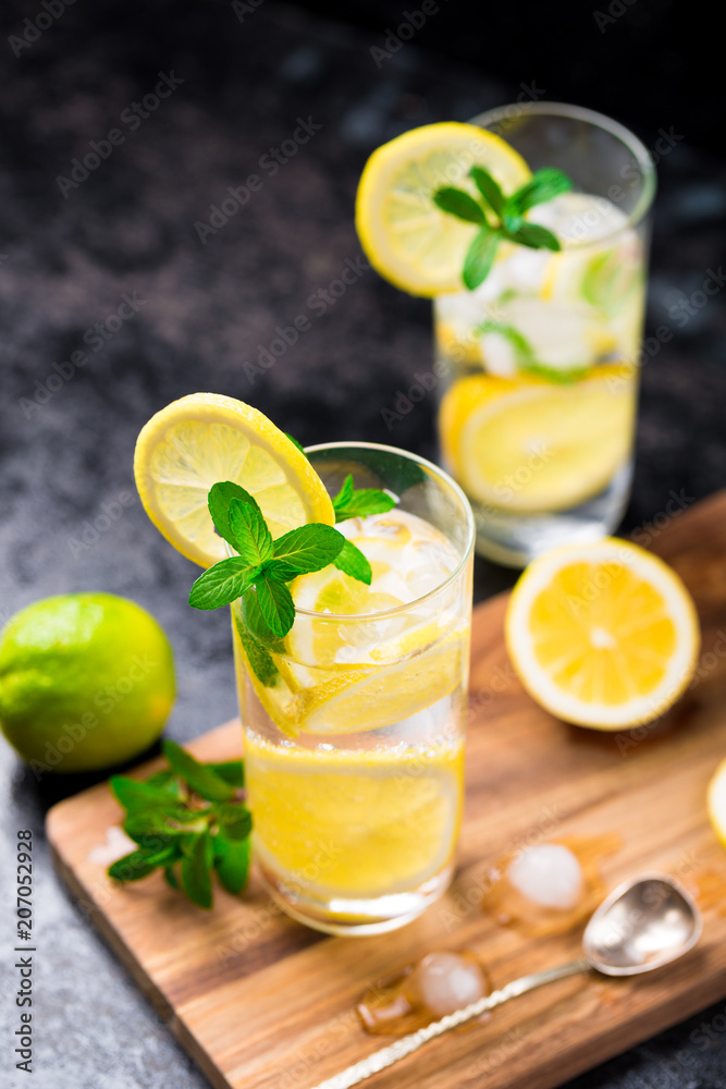 Lemon fruit lime slices caipirinha from Brazil, lemonade mint ice cubes in cold glasses on dark background, alcoholic mojito cockail ice tea green mint leaves, brown sugar spoon, copy space Lemon fruit lime slices caipirinha from Brazil, lemonade mint ice cubes in cold glasses on dark background, alcoholic mojito cockail ice tea green mint leaves, brown sugar spoon, copy space