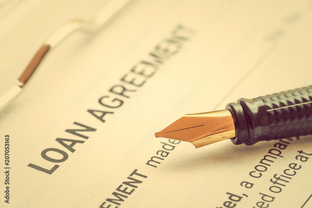 Fototapeta premium Business loan agreement or legal document concept : Fountain pen on a loan agreement paper form. Loan agreement is a contract between a borrower and a lender, a compilation of various mutual promises.