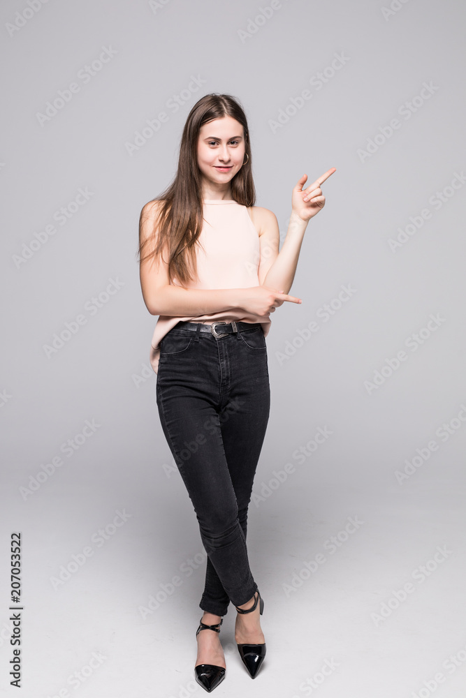 Full length portrait of a smiling girl pointing finger away isolated on white background Full length portrait of a smiling girl pointing finger away isolated on white background
