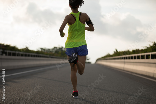 Young fitness woman running on city road