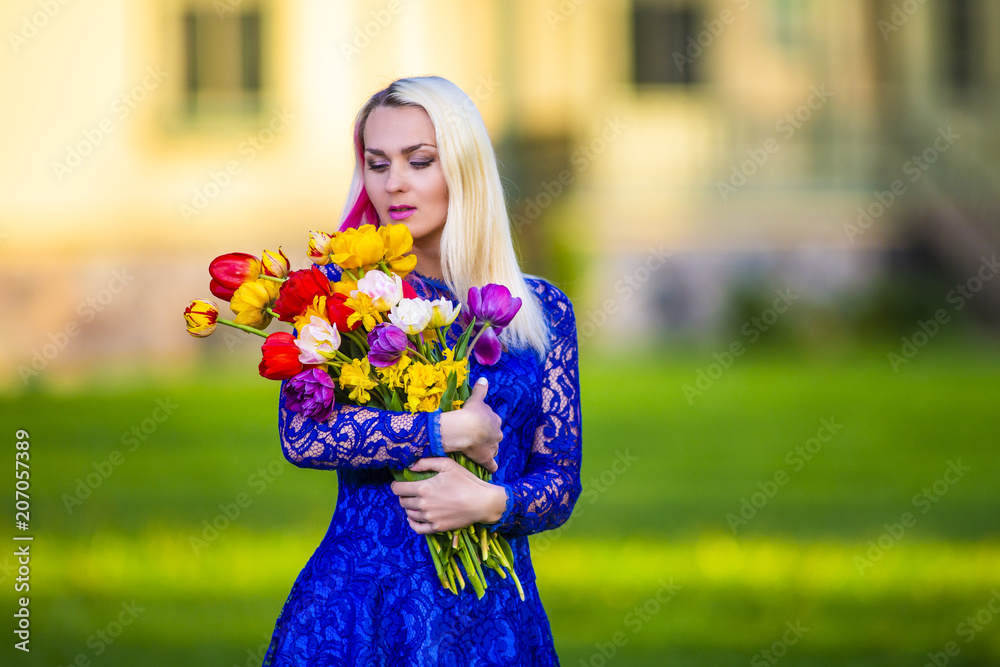 Fototapeta premium Positive Caucasian Blond With Bunch of Tulips. Posing Outdoors.