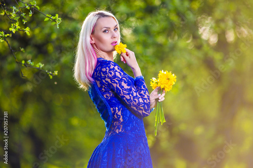 Beauty Concepts. Happy Positive Caucasian Blond With Bunch of Daffodils. Posing in Sunny Summer Forest Outdoors. photo