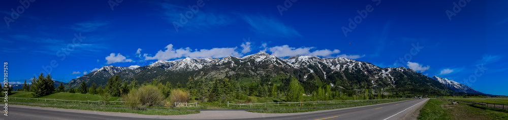 Beautiful panoramic view of Grand Tetons mountains partial covered with snow in the horizont during gorgeous blue sky