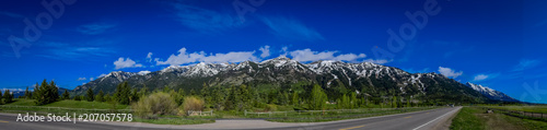 Beautiful panoramic view of Grand Tetons mountains partial covered with snow in the horizont during gorgeous blue sky photo