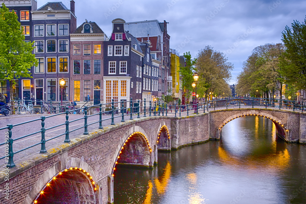 Nighview of Amterdam Cityscape with Its Canals. Illuminated Bridge and Traditional Dutch Houses At Twilight on The Background.