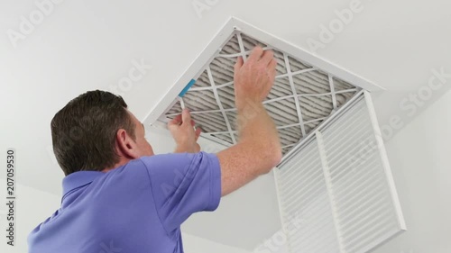 Man Replacing Ceiling Air Filter 
Mature male replacing a dirty air filter with a clean one in a HVAC return duct. Technician changing a dirty air filter for a clean one in a ceiling home air duct.