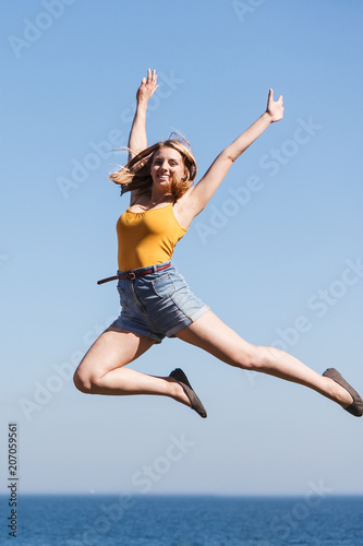 Carefree woman jumping by sea ocean water.