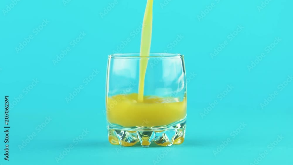 4K close-up shot of milk cold beverage drink pooring into small beautiful glass blue background in studio 4K close-up shot of milk cold beverage drink pooring into small beautiful glass blue background in studio