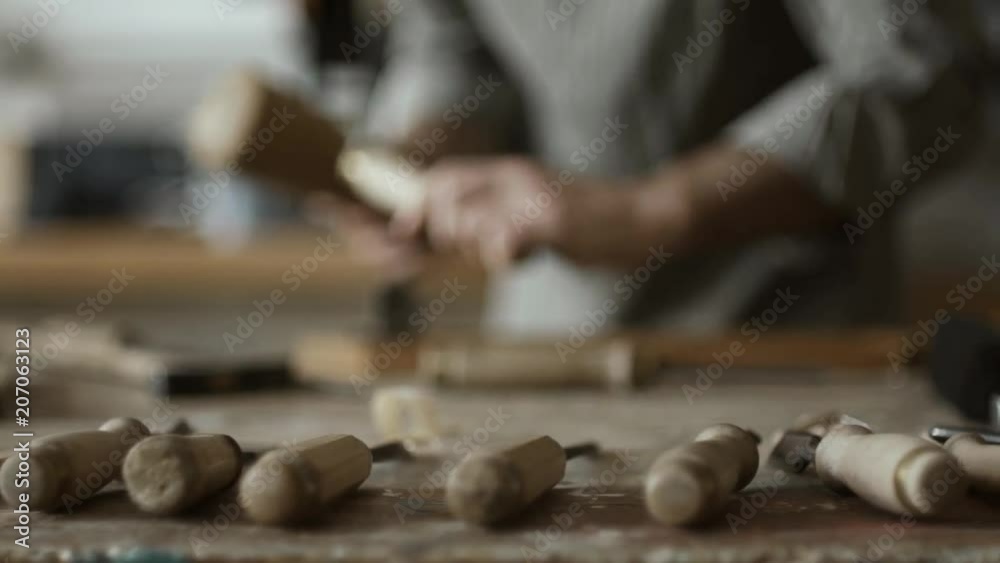 Skilled carpenter carving wood with mallet and chisel