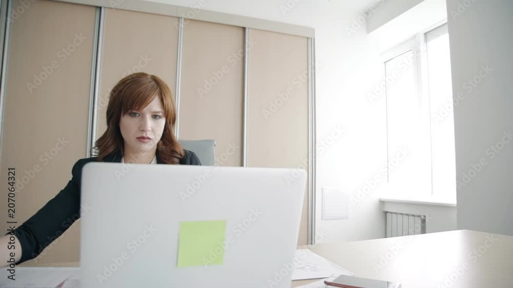 Female specialist works with laptop and documents at table in modern office, beautiful businesswoman in working process in comfortable workplace. Concept: attractive lady, company, employment. Female specialist works with laptop and documents at table in modern office, beautiful businesswoman in working process in comfortable workplace. Concept: attractive lady, company, employment.