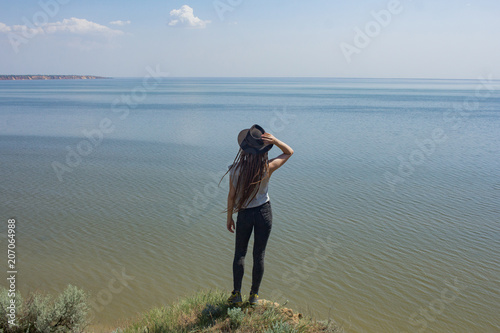minimalistic landscape with clay cliffs and sea and young woman hiker