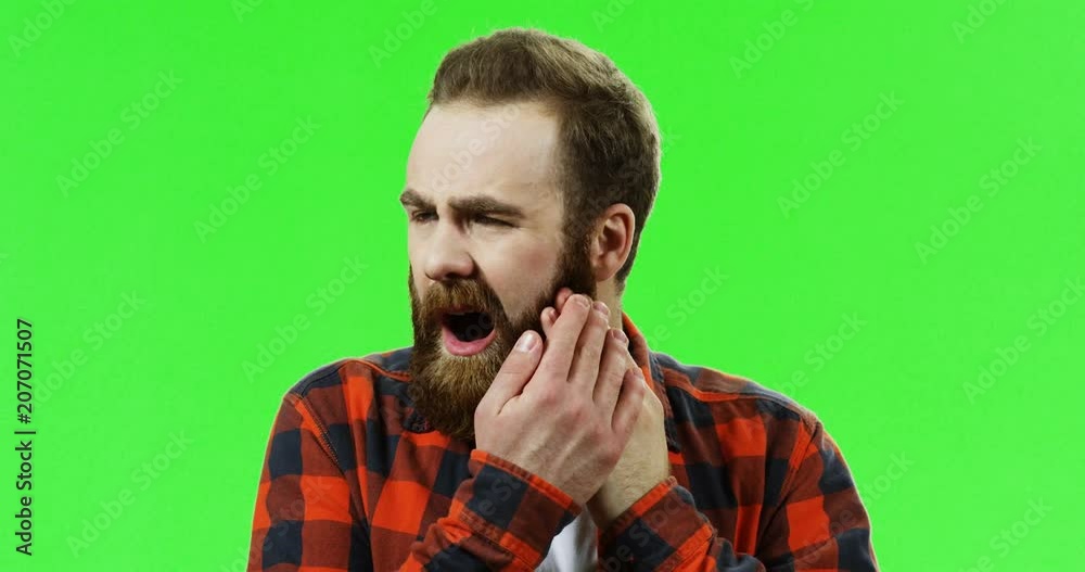 Close up of the man with a red beard having a strong pain in a tooth in front of the camera. Chroma key. Green screen. Close up of the man with a red beard having a strong pain in a tooth in front of the camera. Chroma key. Green screen.