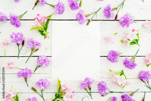 Pattern made of pink flowers and card on white background. Flat lay, top view. Background with paper card 