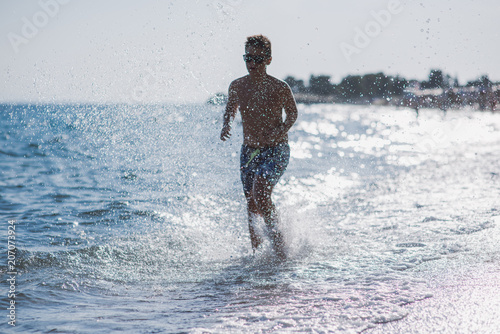 Fototapeta Naklejka Na Ścianę i Meble -  Boy running in water on the beach
