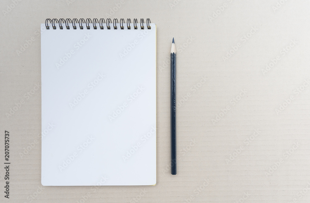 Top view of open spiral blank notebook with pencil on brown background. Top view of open spiral blank notebook with pencil on brown background.