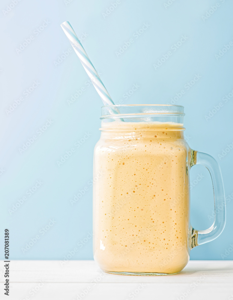 summer drink mango milkshake in mason jar with drinking straw on blue background summer drink mango milkshake in mason jar with drinking straw on blue background