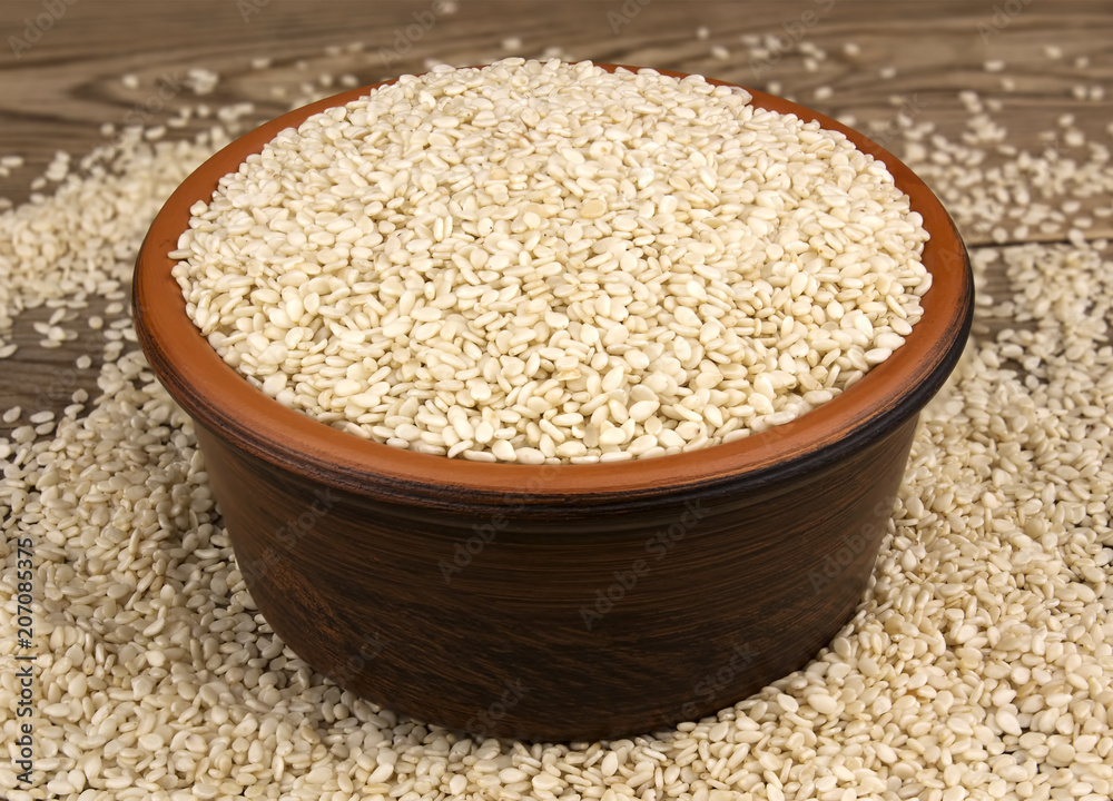 White sesame in a bowl on wooden background White sesame in a bowl on wooden background