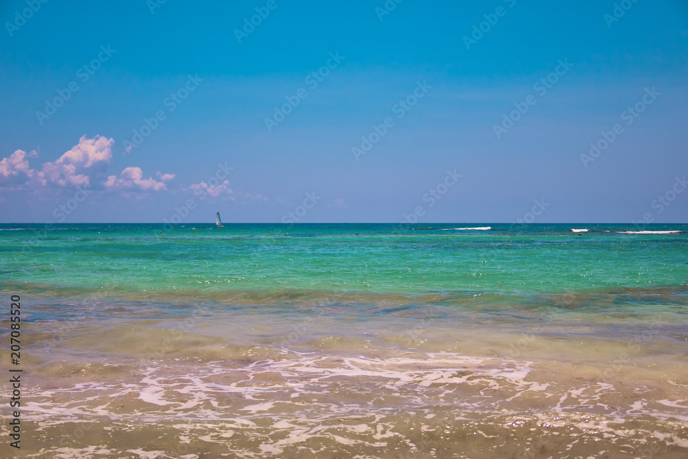 View of tropical beach. Tourists ride parasailing boat with parachute. Sailing yacht sails on waves. Turquoise water of the Caribbean Sea. Riviera Maya Mexico. View of tropical beach. Tourists ride parasailing boat with parachute. Sailing yacht sails on waves. Turquoise water of the Caribbean Sea. Riviera Maya Mexico.