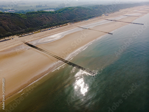 Luftaufnahme eines Strands mit im Meer glitzernder Sonne