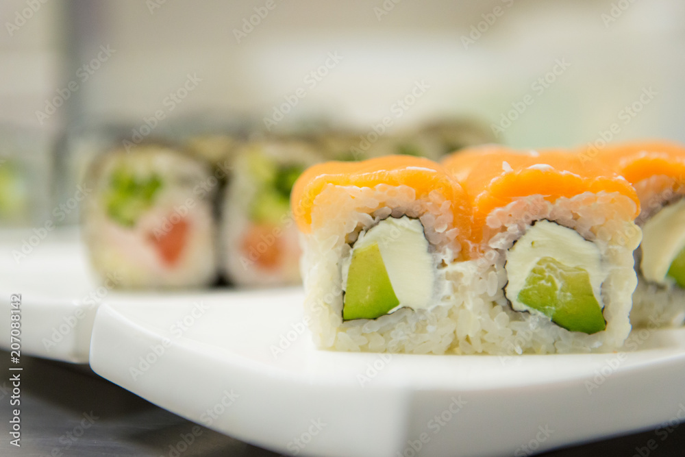 Sushi with salmon and avocado on a platter. Japanese cuisine. Sushi with salmon and avocado on a platter. Japanese cuisine.